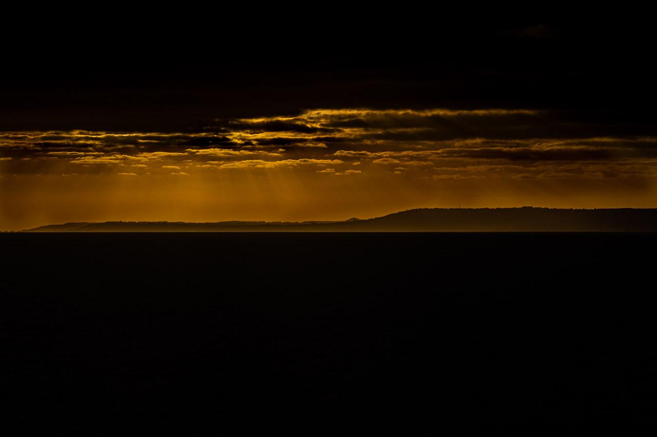 British Sun Kiss, une photographie saisissante où la lumière dorée perce entre les nuages sombres, illuminant les falaises de Douvres.