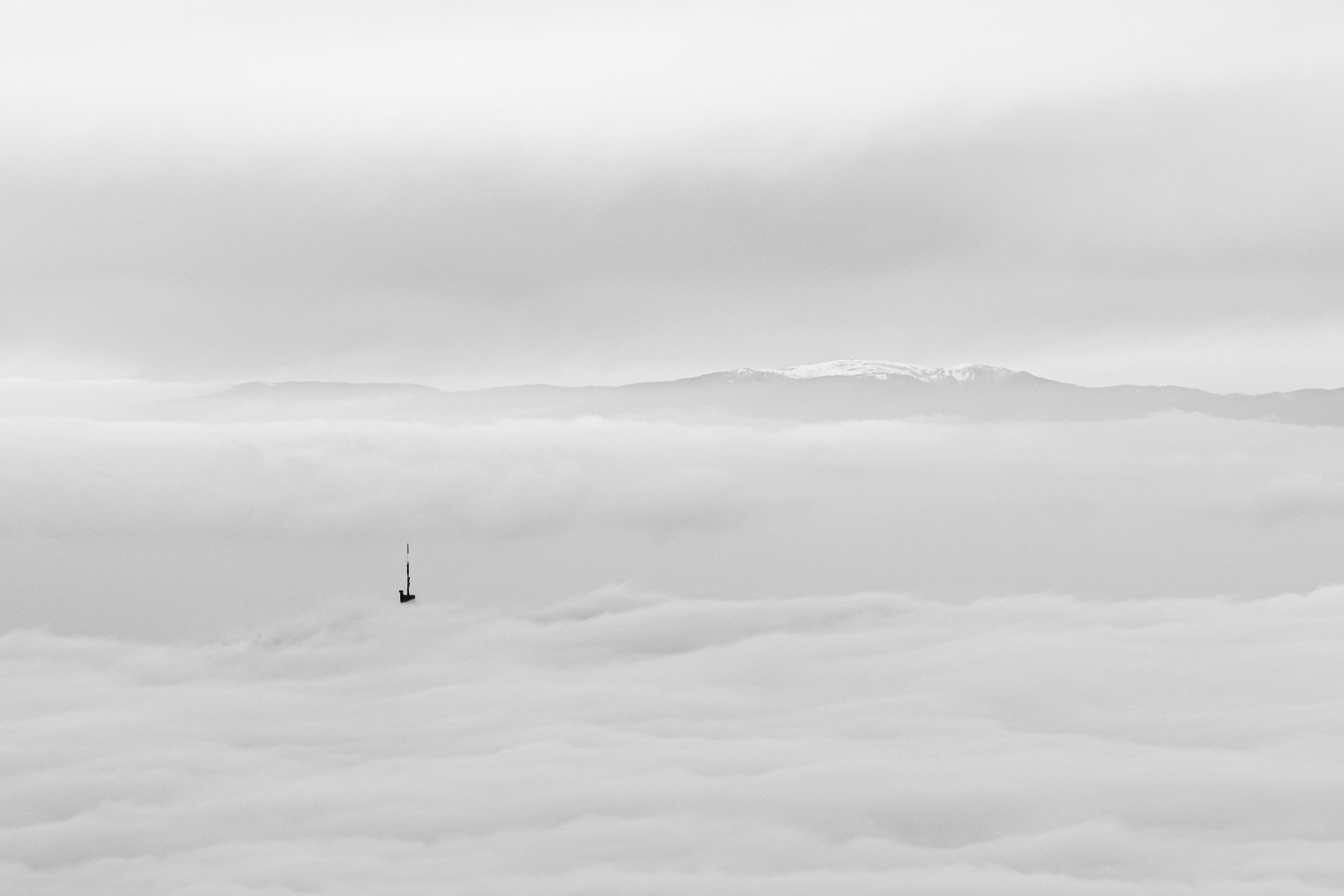 L'antenne qui voulait être montagne, une photo en noir et blanc sereine et apaisante, capturant la beauté des montagnes suisses et la douceur des nuages.